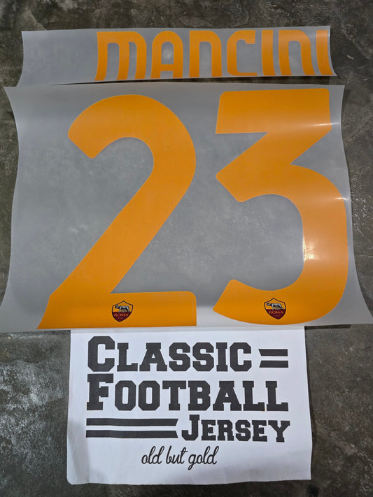 Two printed items on a textured surface, one with '23' and 'Mancini', the other with 'Classic Football Jersey'.